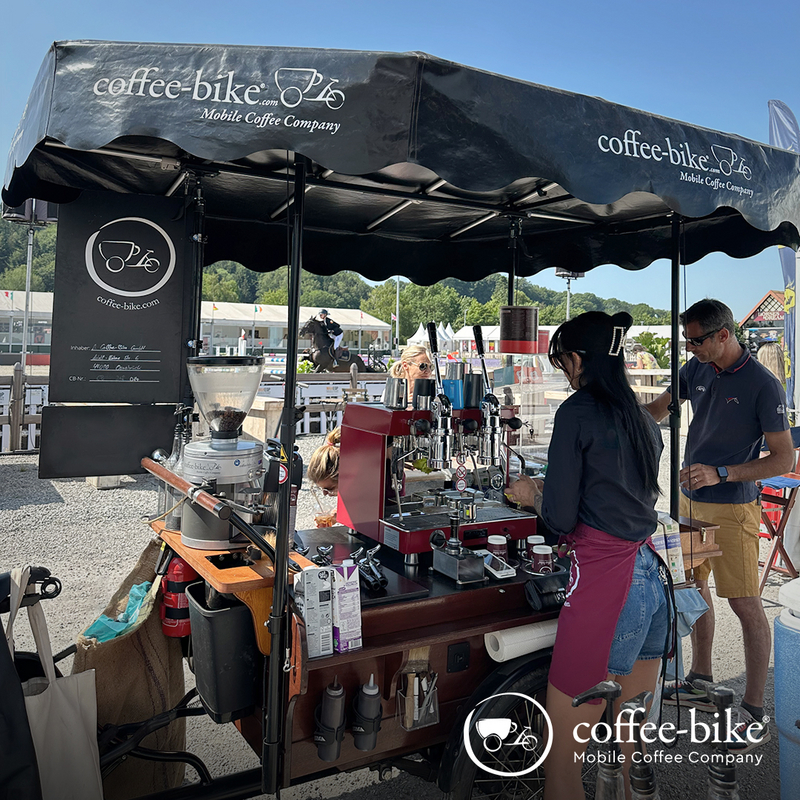 [Translate to UK:] A Coffee-Bike with Barista and customers at a equestrian festival