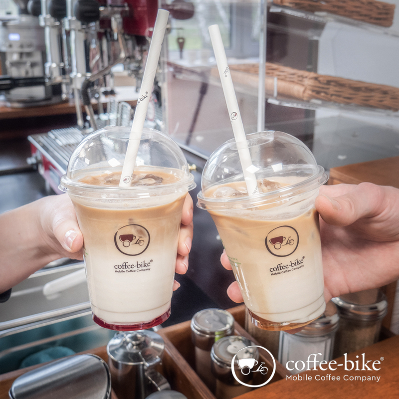 Zwei Summer Specials in Clear Cups mit Strohhalmen, die von Händen gehalten werden