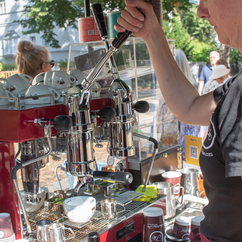 The lever of a portafilter machine is operated by a person, under it a white Coffee-Bike cup