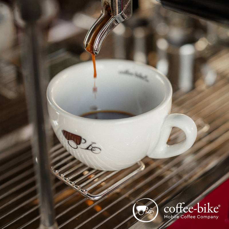 Frisch gebrühter Espresso fließt aus einer Siebträgermaschine in eine Coffee-Bike-Tasse.