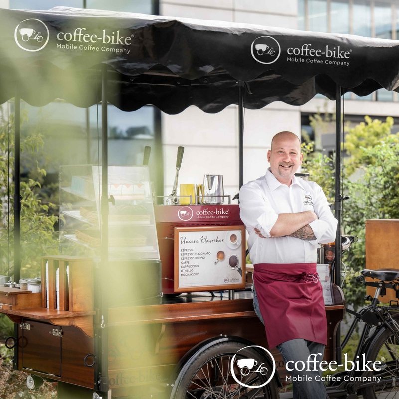 Unternehmer lehnt an seinem Coffee-Bike, der mobilen Kaffeebar