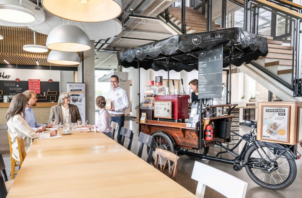 Coffee-Bike sitzen vor der mobilen Kaffeebar bei einer Franchise Informationsveranstaltung