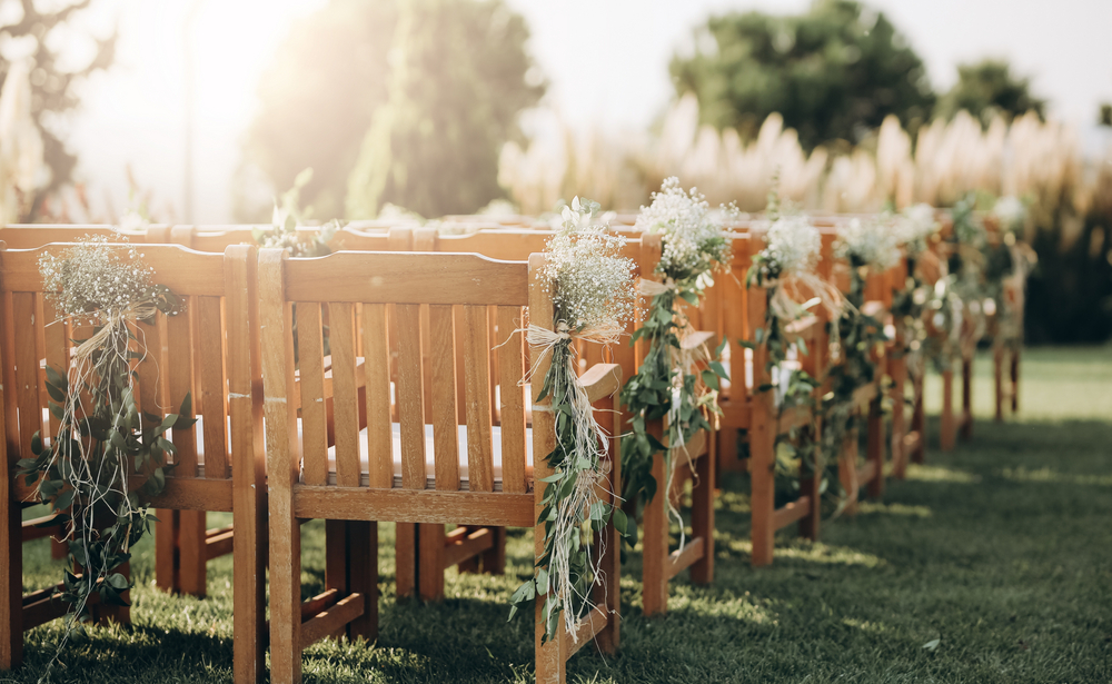 Freie Trauung im Grünen mit Holzbänken und Blumen als Deko.