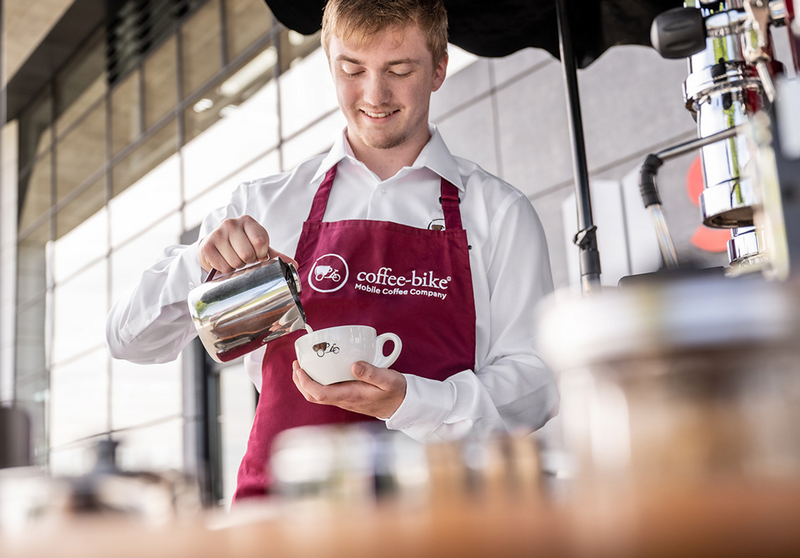 [Translate to UK:] A barista prepares a coffee speciality in a Coffee-Bike cup