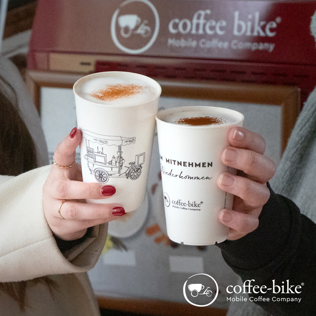 Zwei Hände halten zwei Kaffeespezialitäten im Becher.
