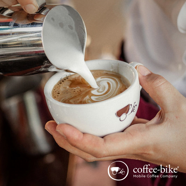 Milch wird in eine Coffee-Bike Tasse gegossen