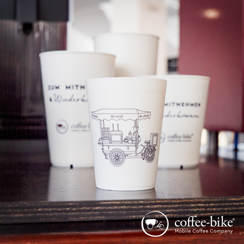 White cups in various sizes are placed on the shelf of the Coffee-Bike