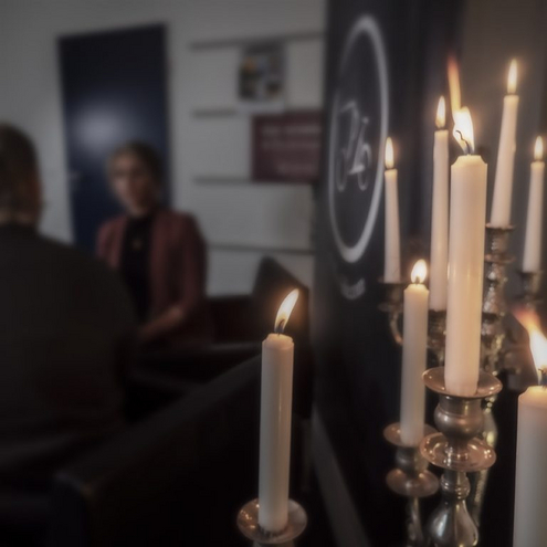 On the right white candles are burning, on the left in the background you can see a woman out of focus