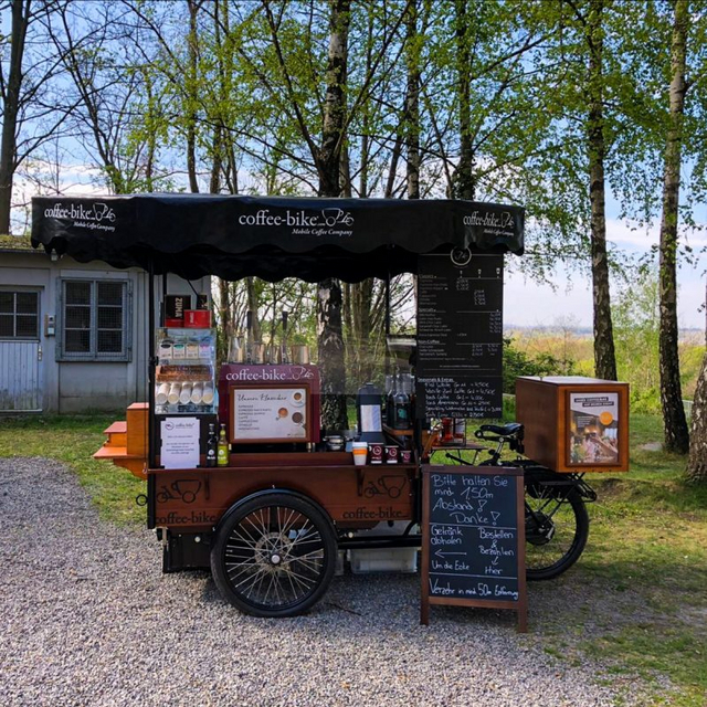 Coffee-Bike steht in der Natur mit einem Aufsteller vor dem Bike