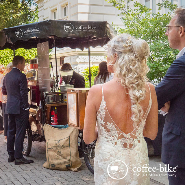 A bride and groom stand in front of the Coffee-Bike