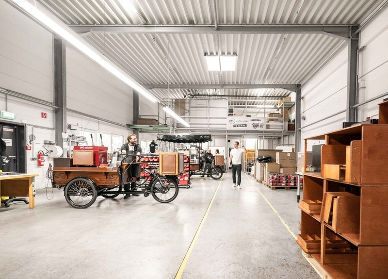 Produktionshalle der Coffee-Bike GmbH mit Ingenieuren, die an den Coffee-Bikes arbeiten