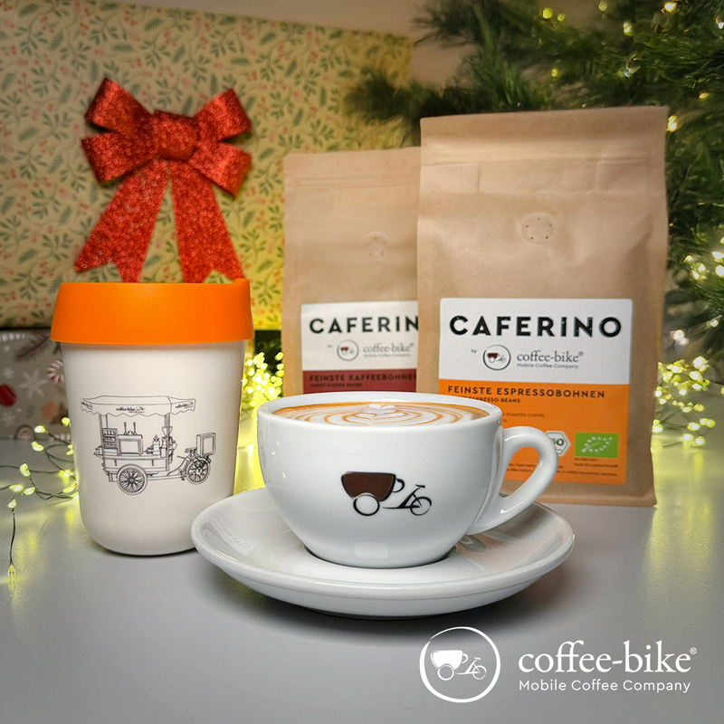 White Cup with Coffee-Bike logo stands in front of a coffee to-go mug and pack of coffee beans
