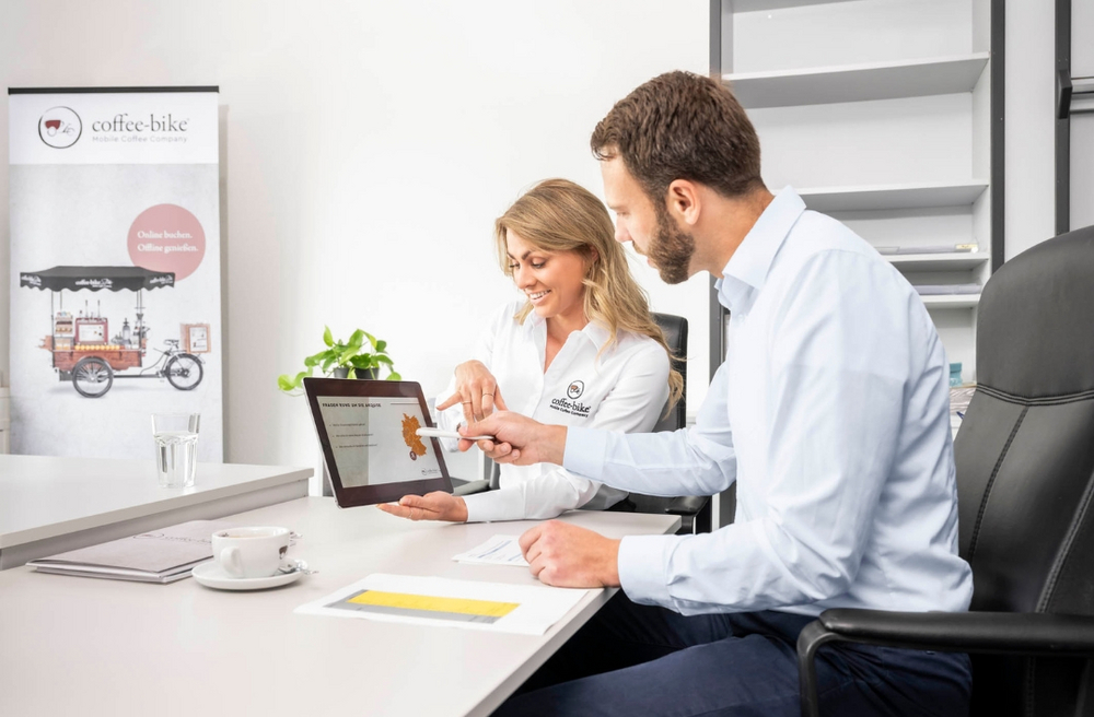 Mann und Frau informieren sich über die Selbstständigkeit mit Coffee-Bike