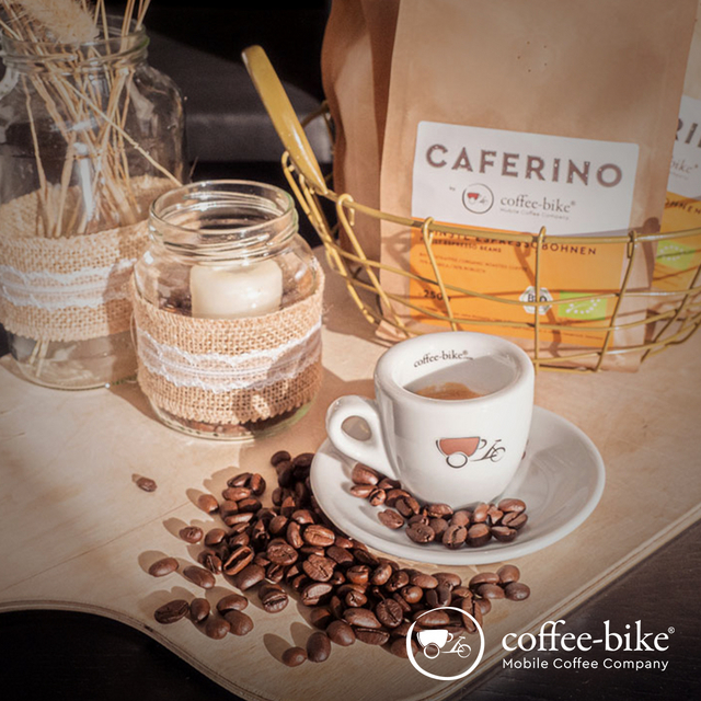 [Translate to UK:] Espresso cup with beans, in the background Caferino package and candles