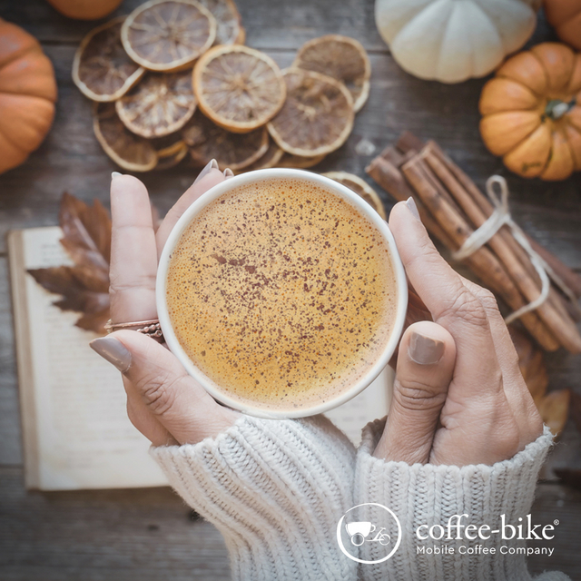 [Translate to UK:] Hands holding a Pumpkin Spice Latte, background decorated with autumn stuff