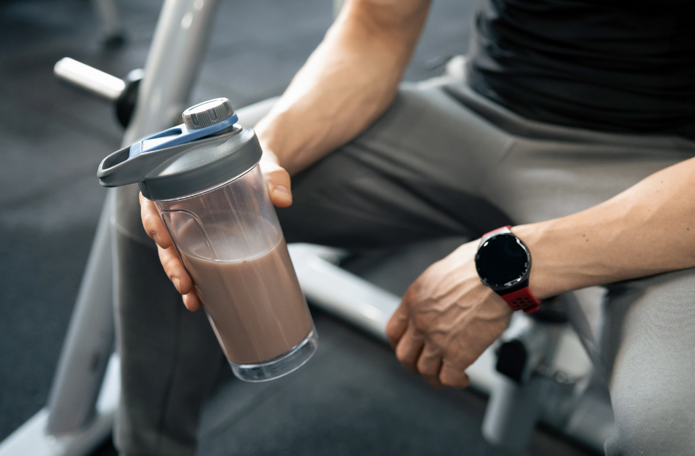 Sportler hält einen Protein Kaffee in der Hand 