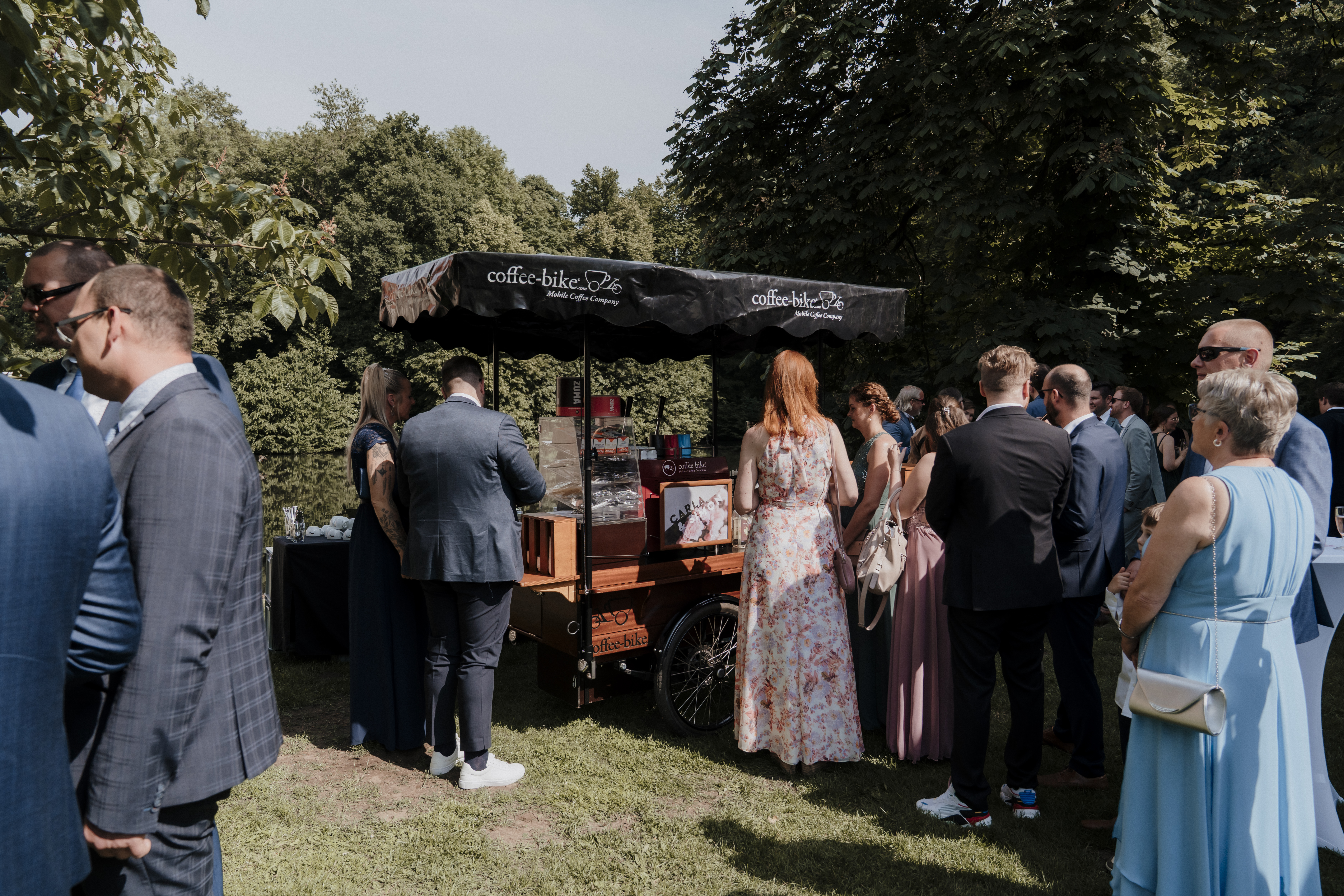 Das Coffee-Bike als Kaffeebar auf einer Hochzeit mit Hochzeitsgästen im Vordergrund.