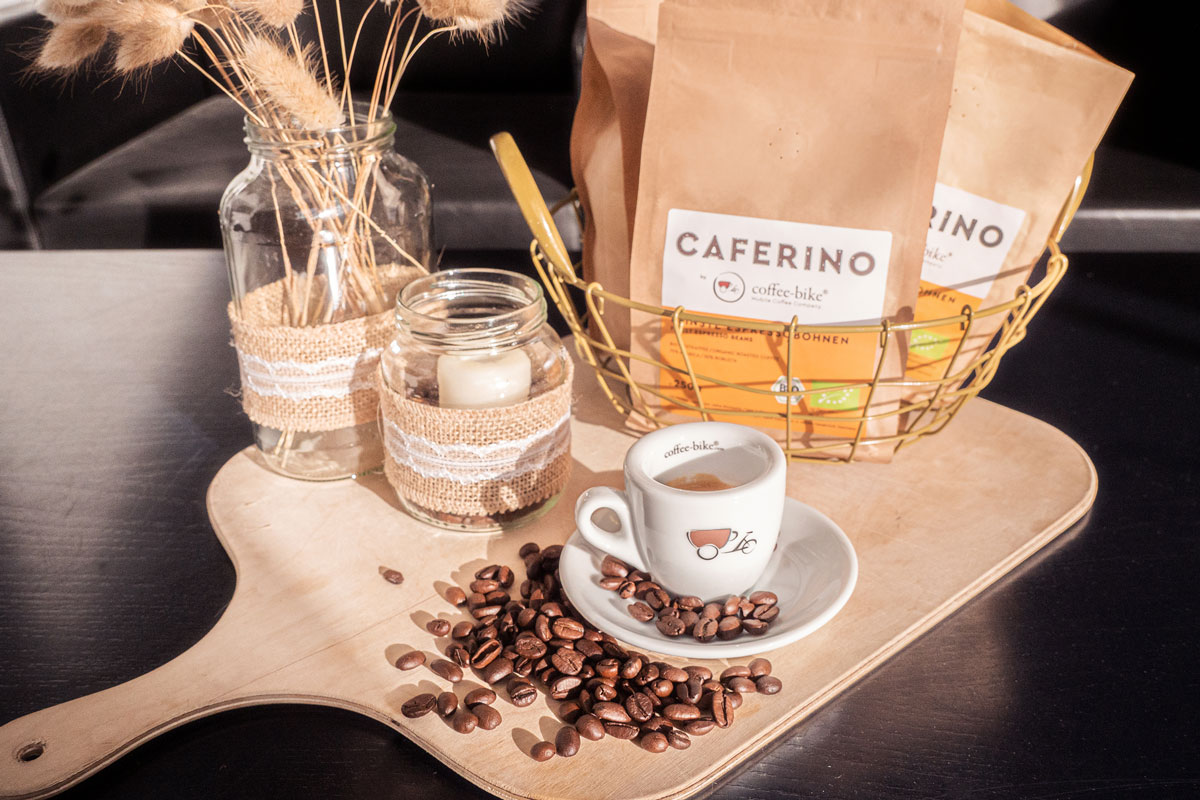 Tavă cu boabe de cafea Caferino organic epspresso pe o masă cu o ceașcă și boabe individuale