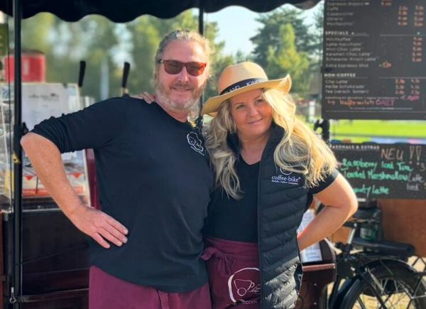 Coffee-Biker Cay Wübbeler steht mit einer Barista vor seinem Coffee-Bike