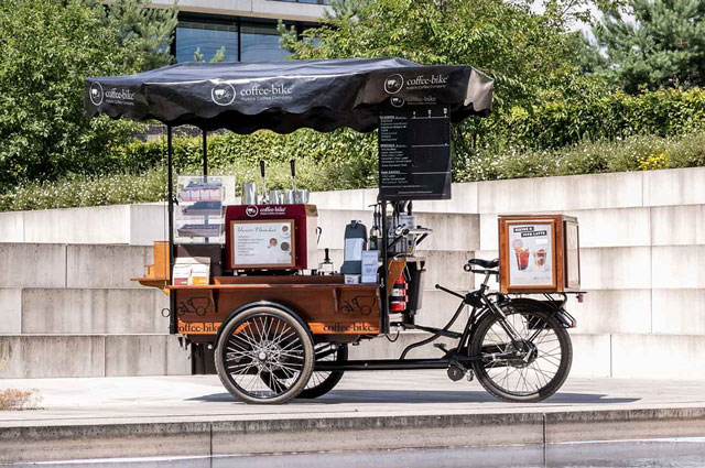 Coffee-Bike in Verkaufssituation vor einer Betonwand im Grünen